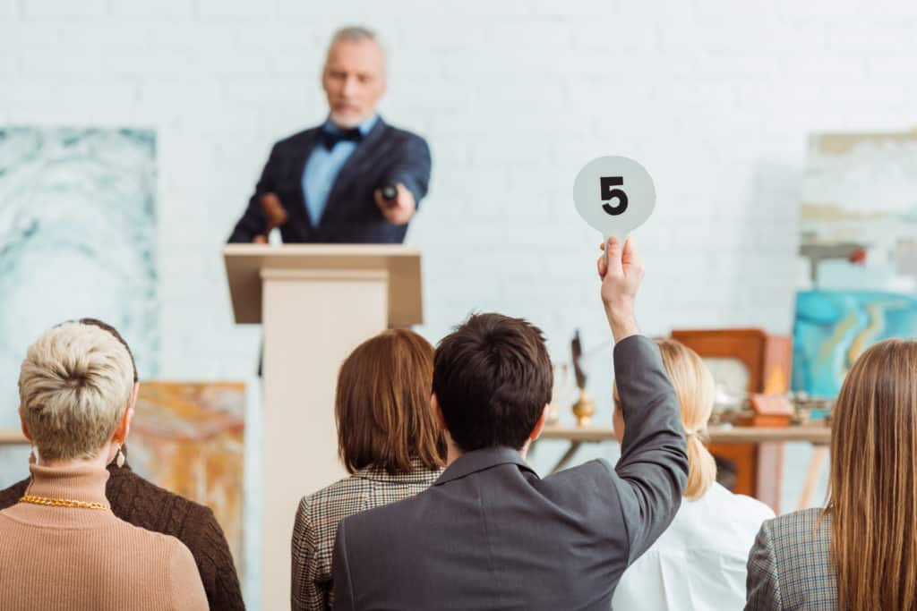 Man bidding at an art auction after identifying his art style.