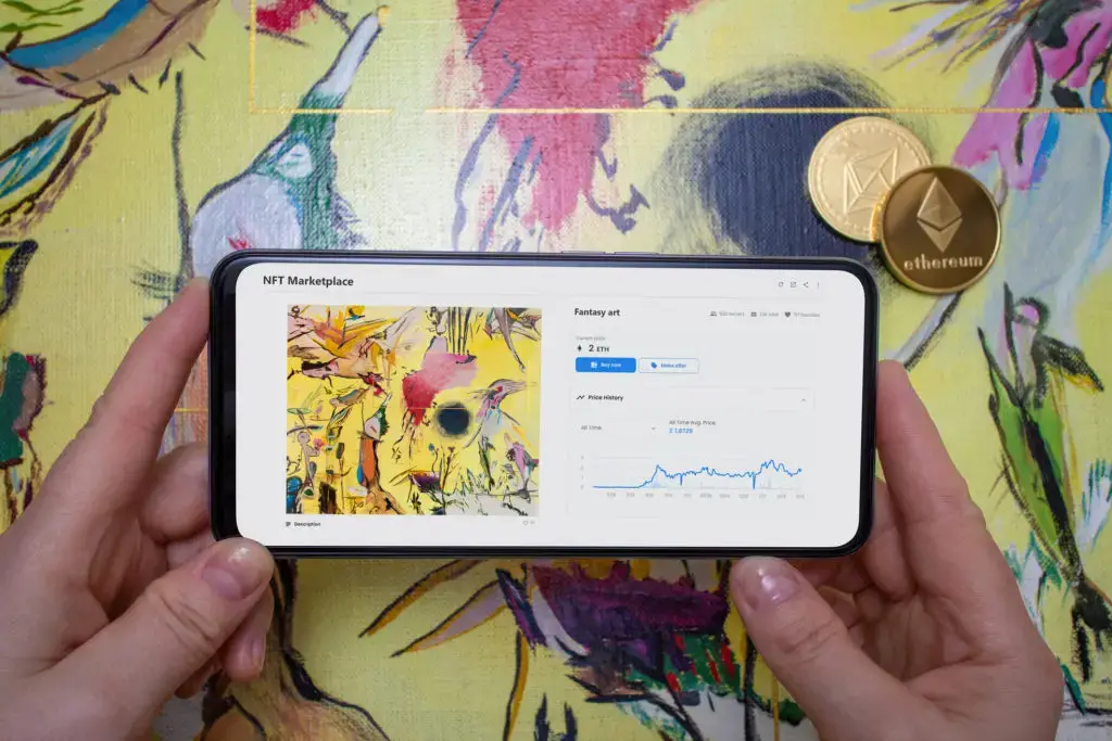 Hands holding a phone tracking the value of an NFT.