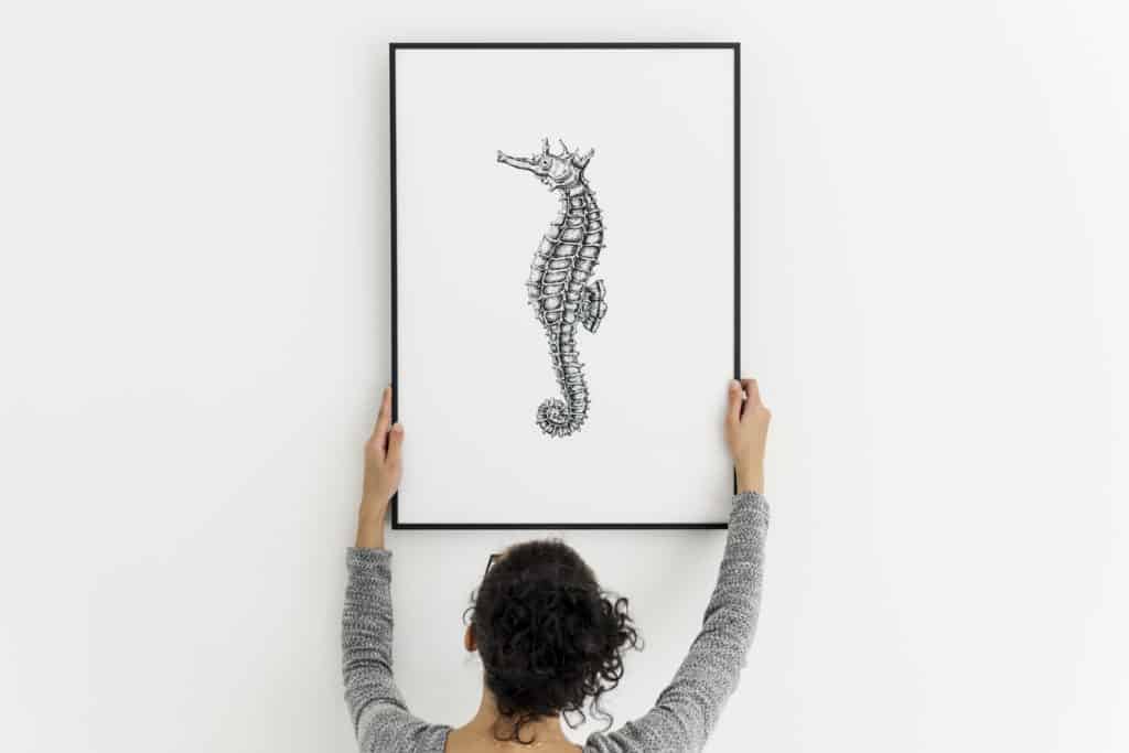 Woman displaying art in her home, but hanging the print too high.