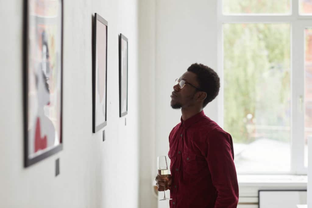 Man staring at illustrations in a gallery after learning what is art appreciation