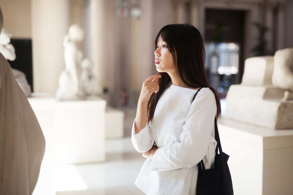 Woman looking at sculpture in a museum to learn what is art appreciation