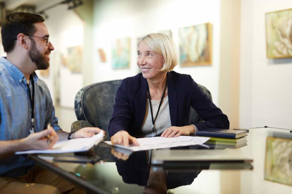 Man and woman in gallery discussing the value of authenticating art.