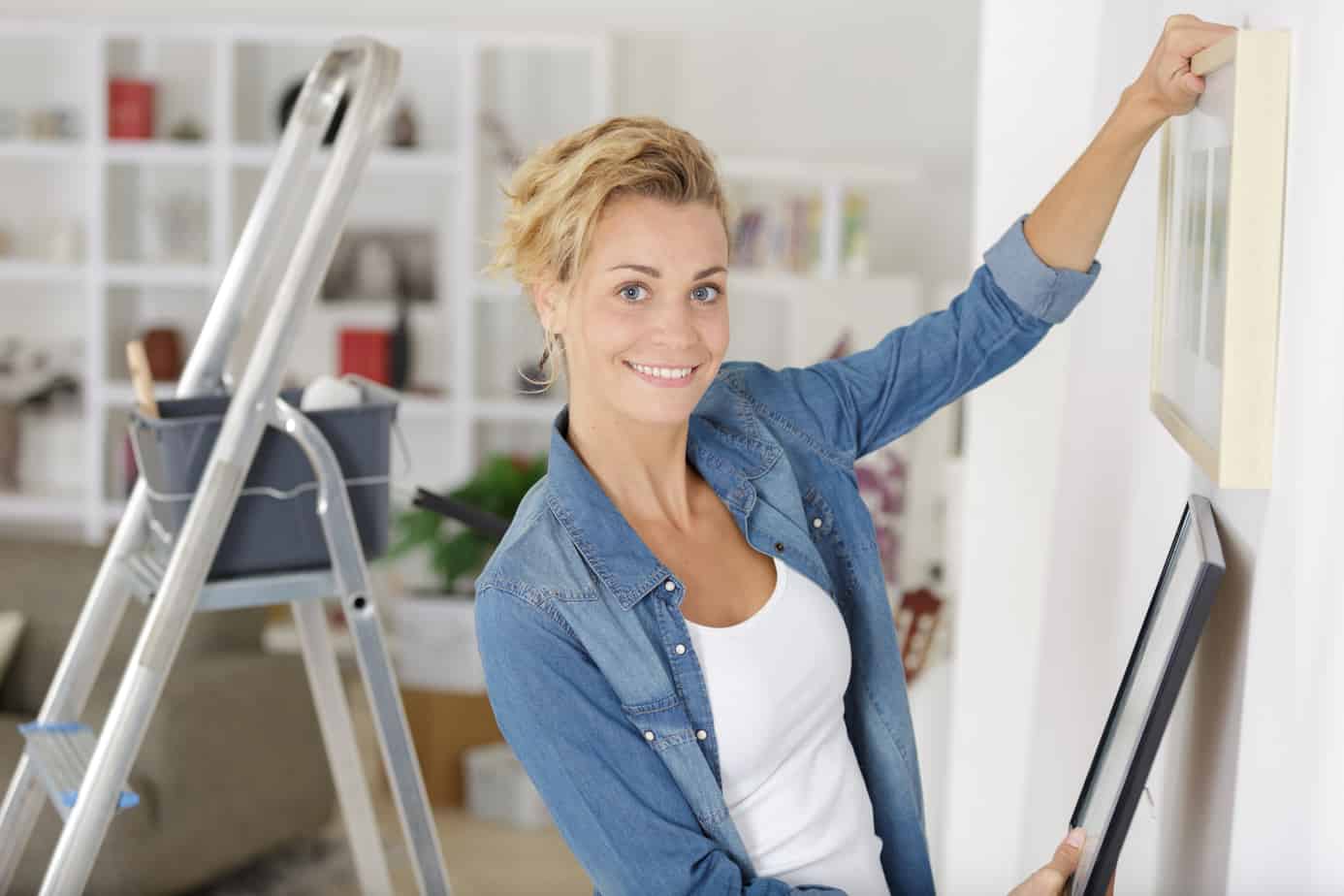 Woman hanging art in her living room after having identified her art style.