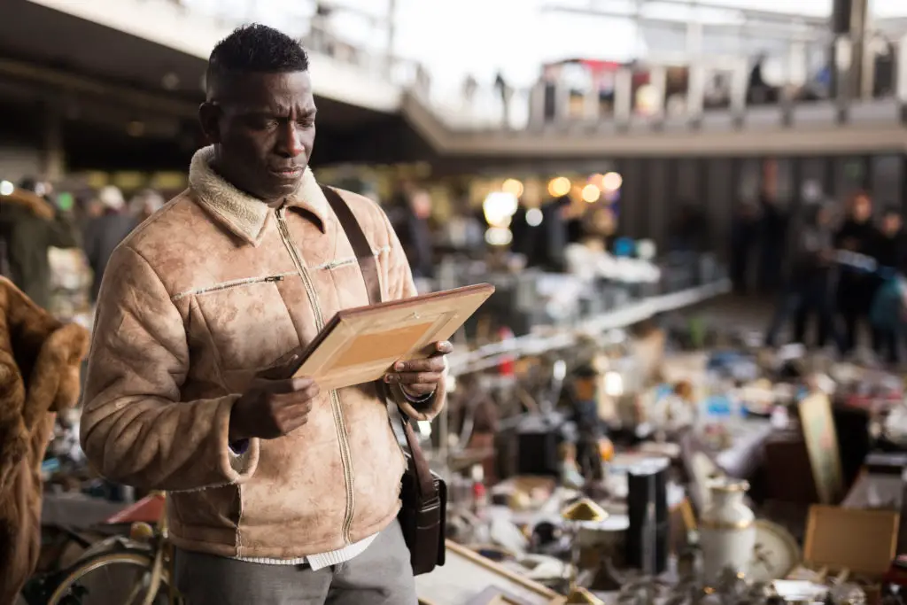 Man at a flea market where he's can buy art on a budget