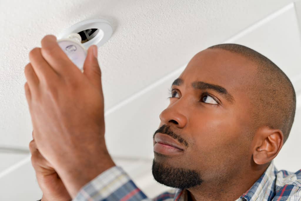 Man installing ceiling bulb having just learned how to light wall art