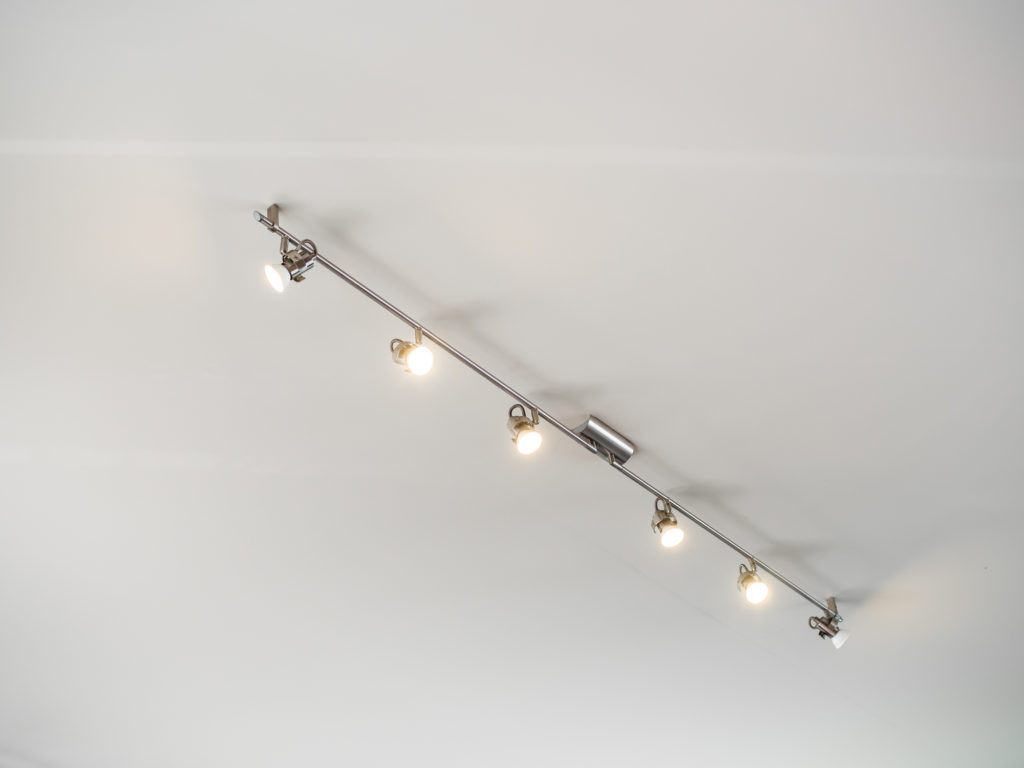 Modern stainless steel track light hanging on white ceiling