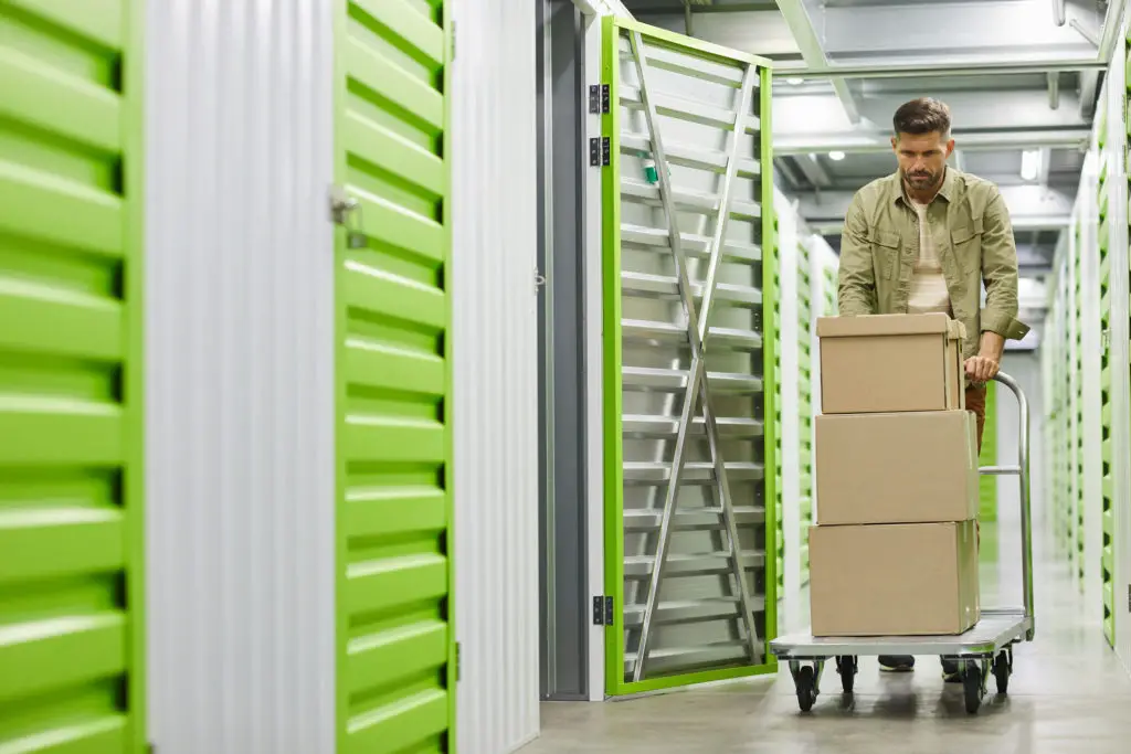 Man pushing cart in self storage having learned how to store artwork