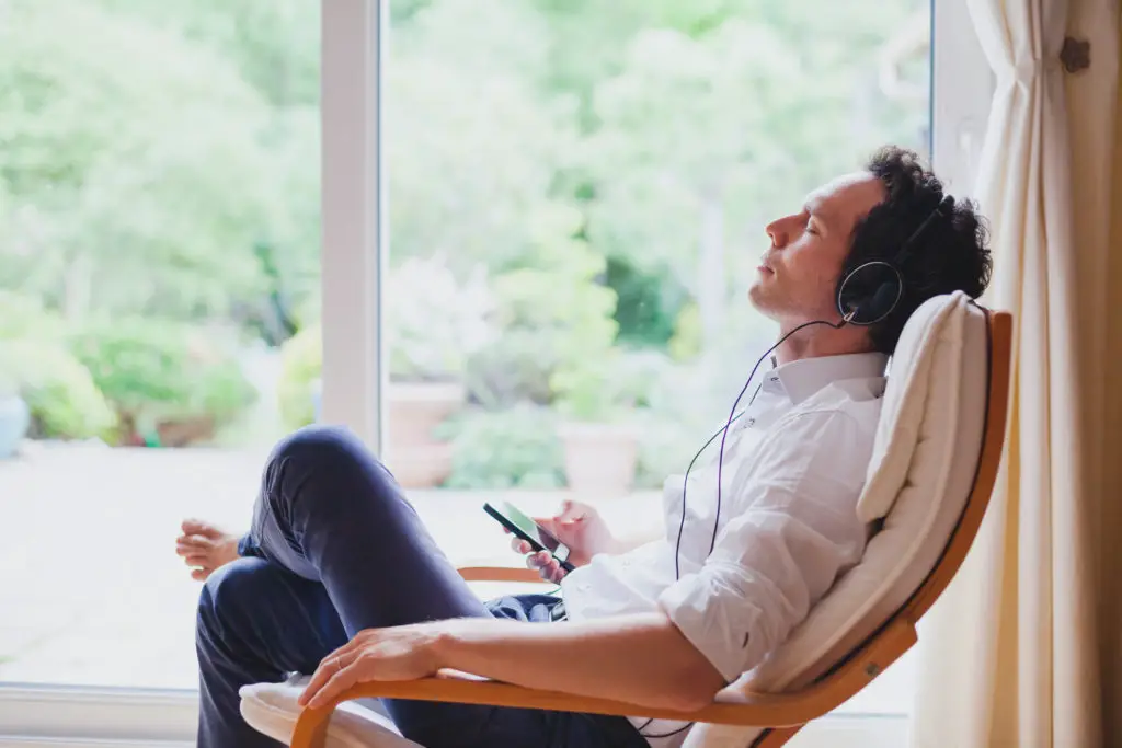 Man sitting in armchair listening to podcast to encourage creativity.