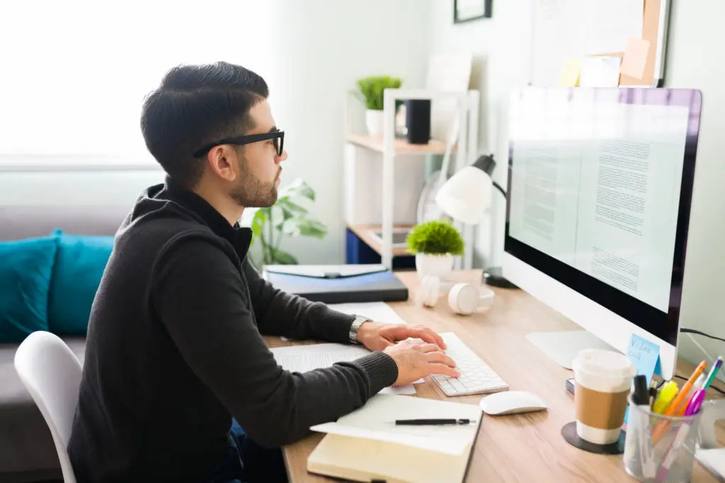 Young male writer with glasses at his computer.