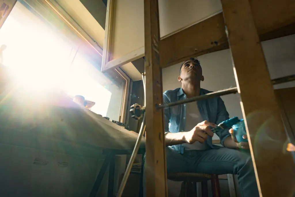 Man looking up at his easel wondering is art really necessary