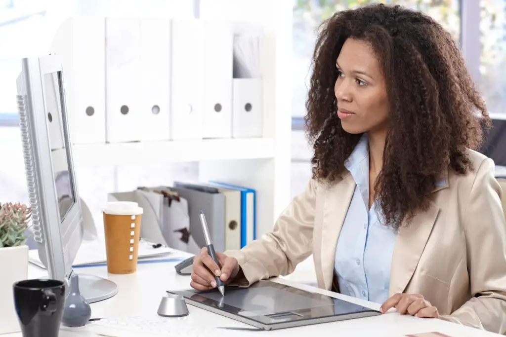 Professional woman using a electronic sketch pad in front of a computer appreciating her knowledge of drawing vs painting