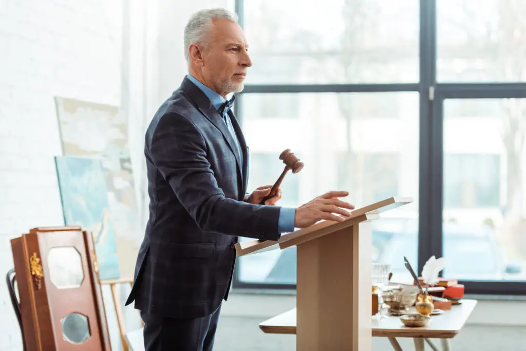 Man at a podium during an art auction using his auctioneer chant to sell art