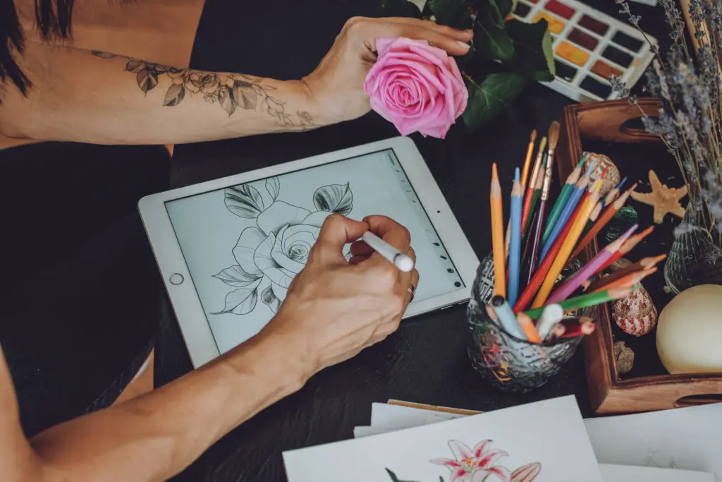 Tattoo artist using digital sketchpad to draw rose.