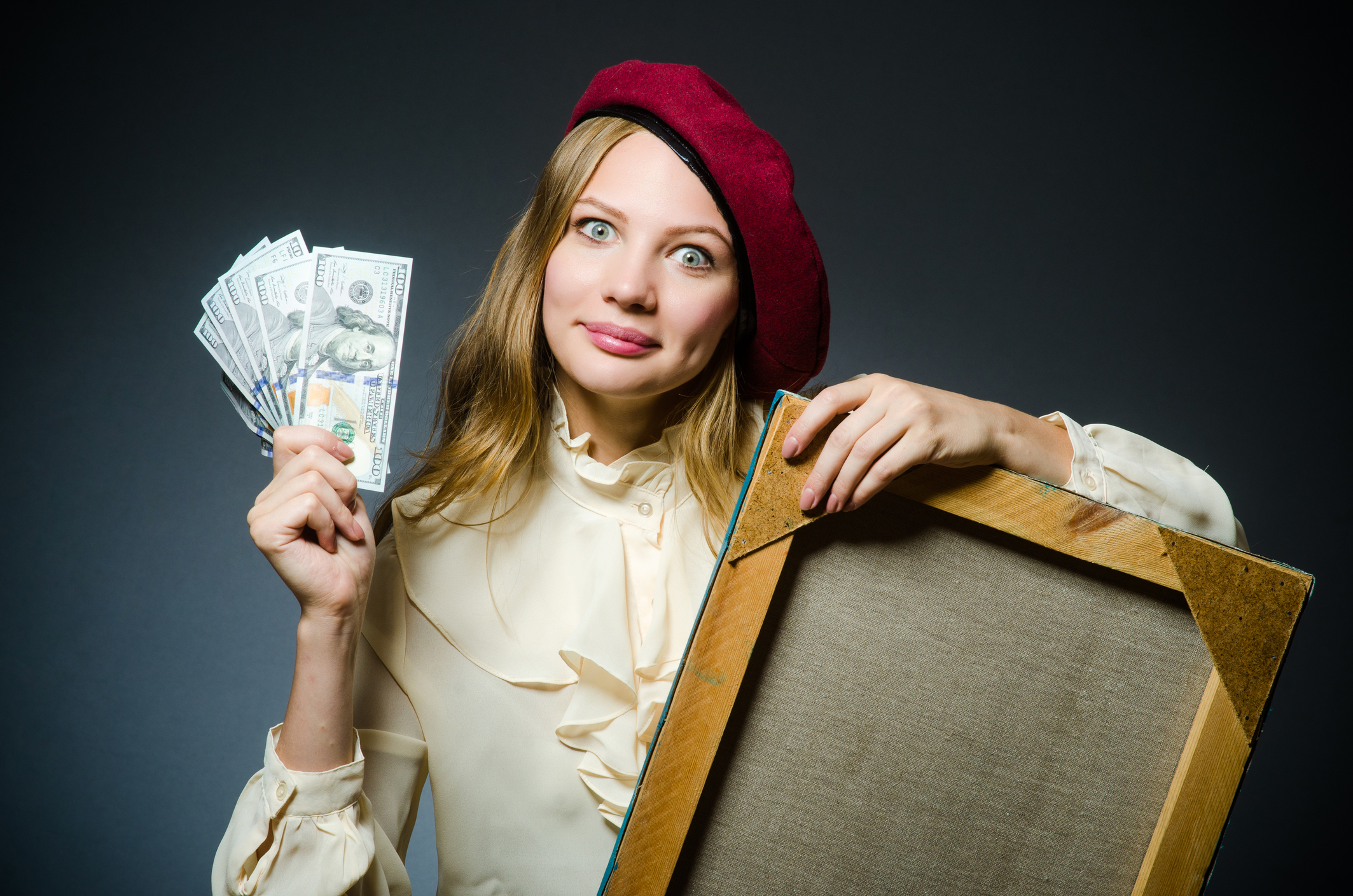 Female artist wearing a beret and holding a canvas in one hand and cash in the other.