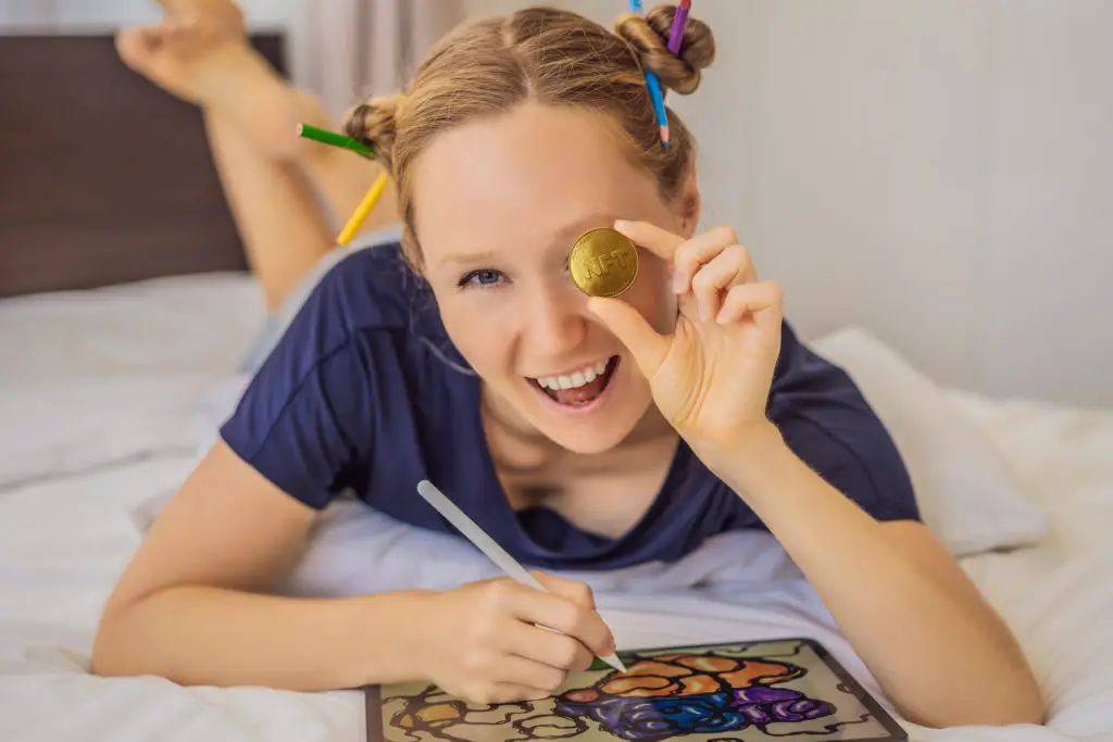 Young, female digital artist with buns in her hair holds an NFT coin.