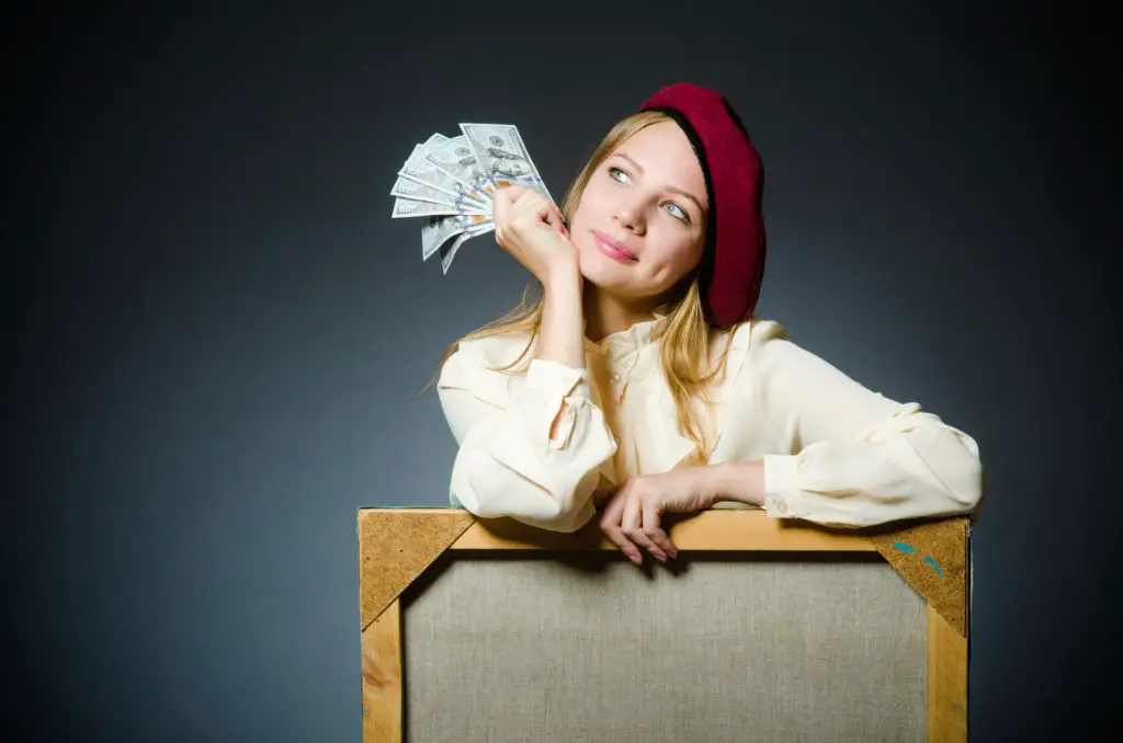 Artist in beret holding cash and thinking about how much to charge for painting.