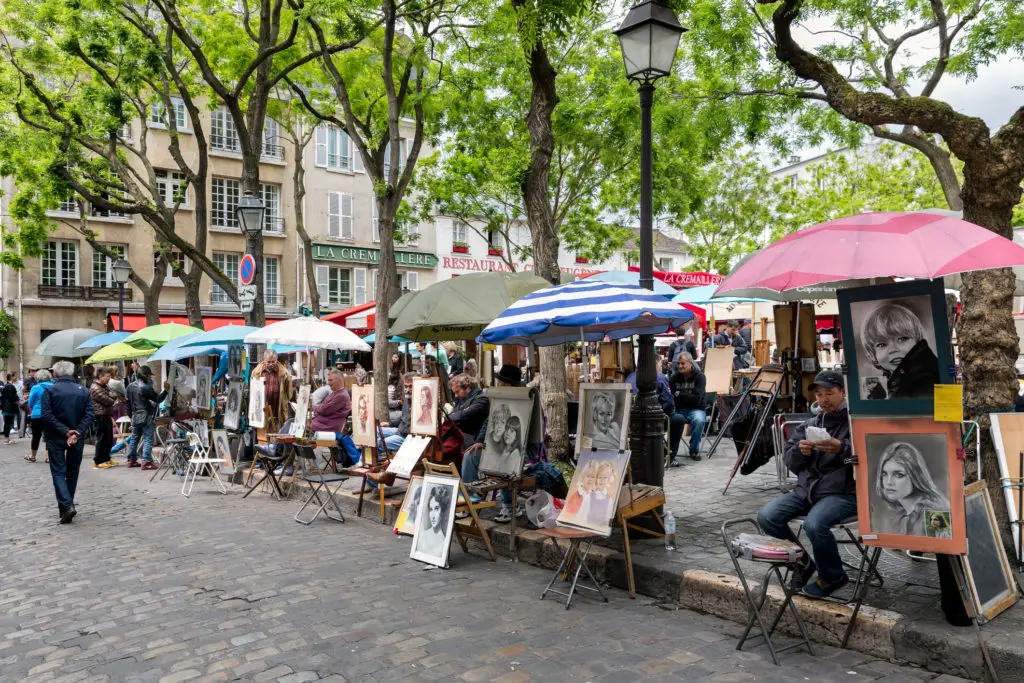 Row of portrait artist stands in Paris who charge similar prices but paint in different styles.