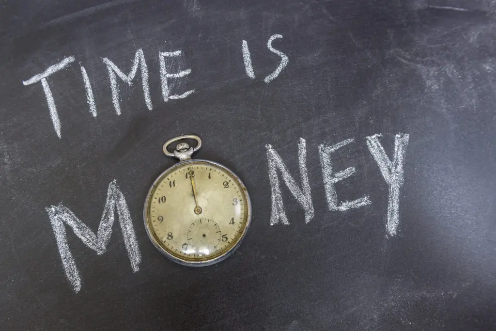 Time is money written on a chalkboard with a pocket watch as the "o" in money.