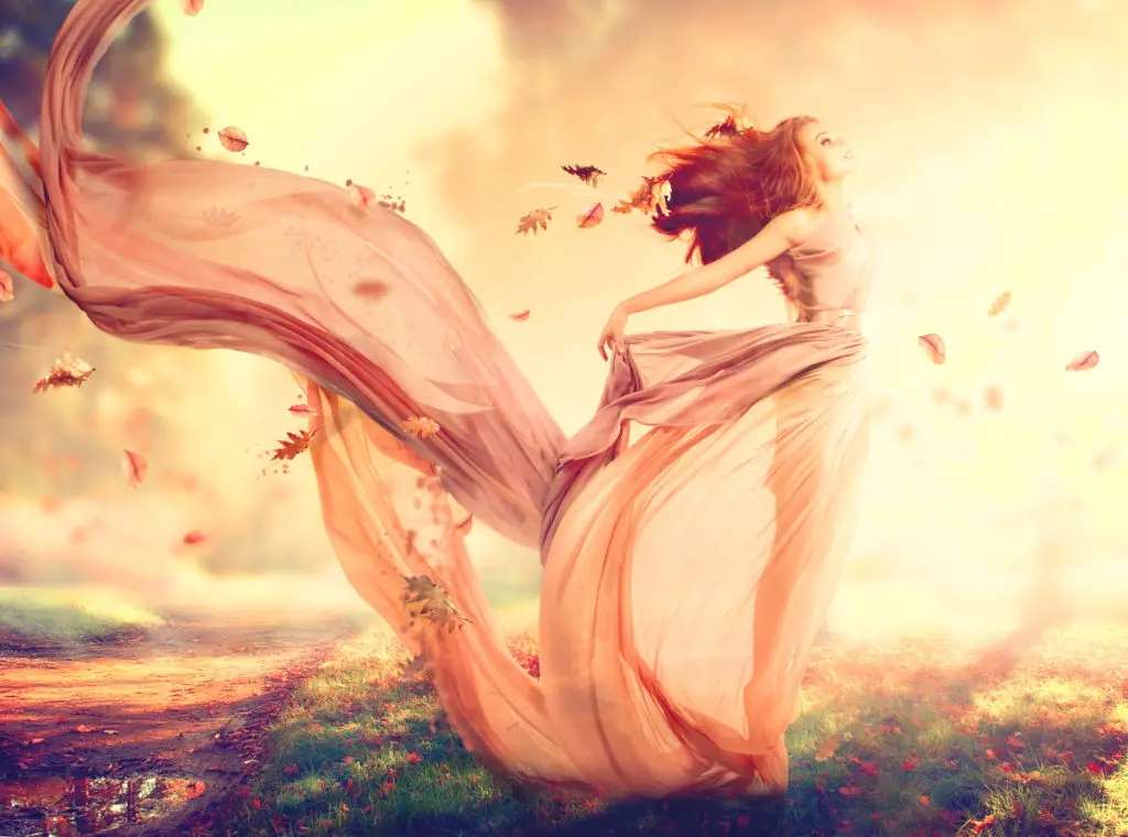 Autumn themed image of woman with red hair in a blowing pink chiffon dress created by AI.