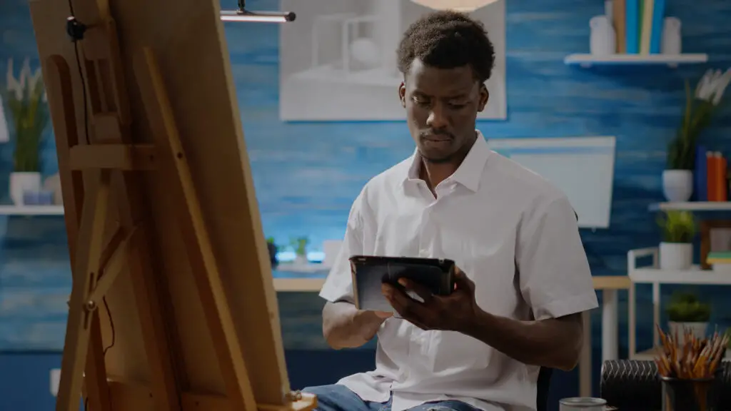 Artist at easel holding a tablet to create AI art.