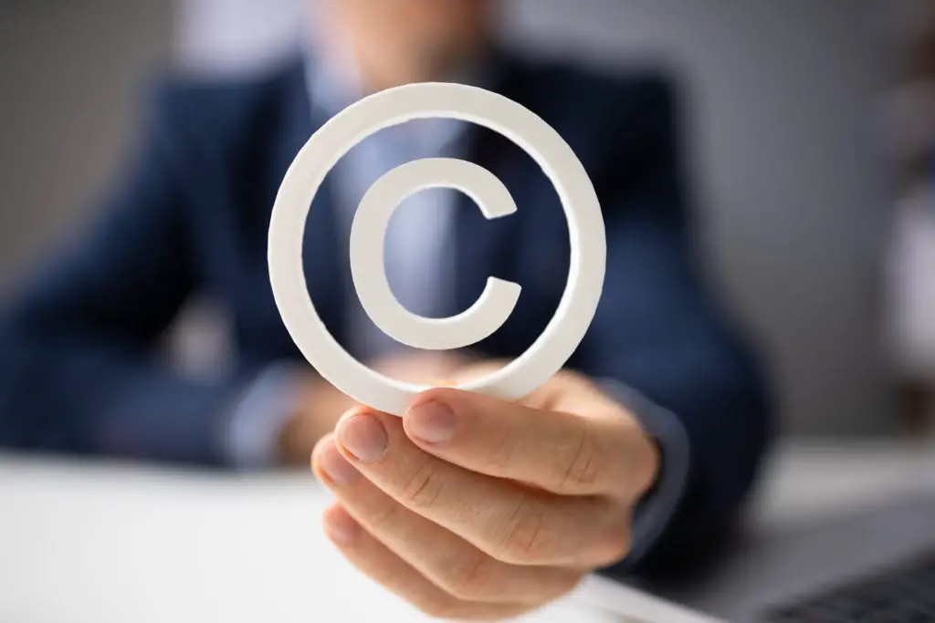 Man in a suit holding a copyright symbol in his hand.